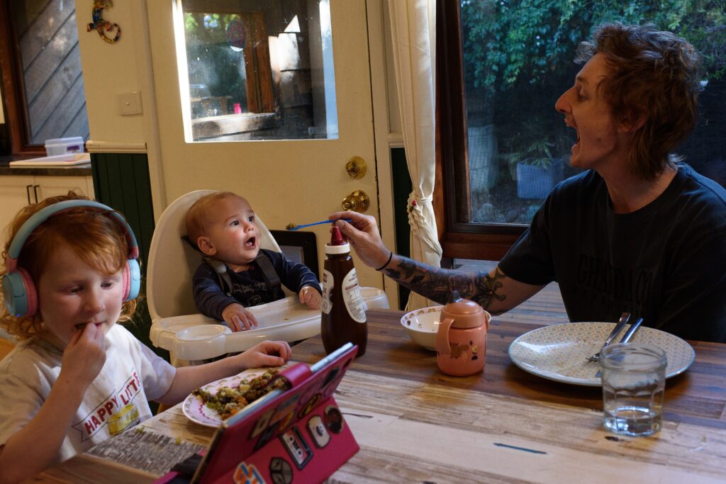 A father feeding his infant son at dinnertime. 